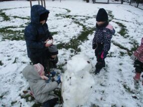 Drei Kinder bauen einen Schneemann