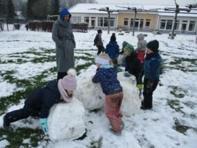 Kinder und Erzieherin mit großen Schneekugeln