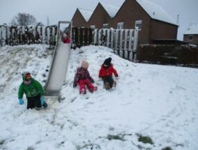 Kinder rutschen Hügel mit Schnee hinunter