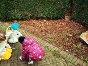 Kinder kratzen Fugen vor Wildblumenwiese aus