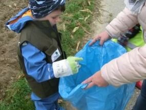 Ein Junge sammelt Müll vom Wegesrand auf