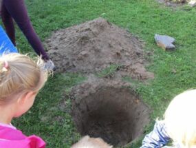 Die Kinder betrachten das Loch für den Apfelbaum
